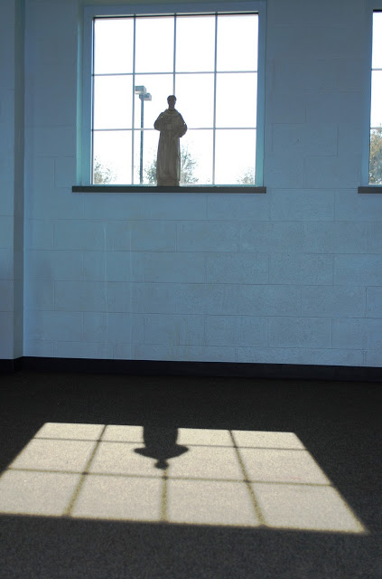 The shadow of St. Francis inside the kids' school gymnasium. Lord make me an instrument...