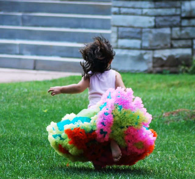 Little Girl Running in Grass wearing a big colorful skirt 